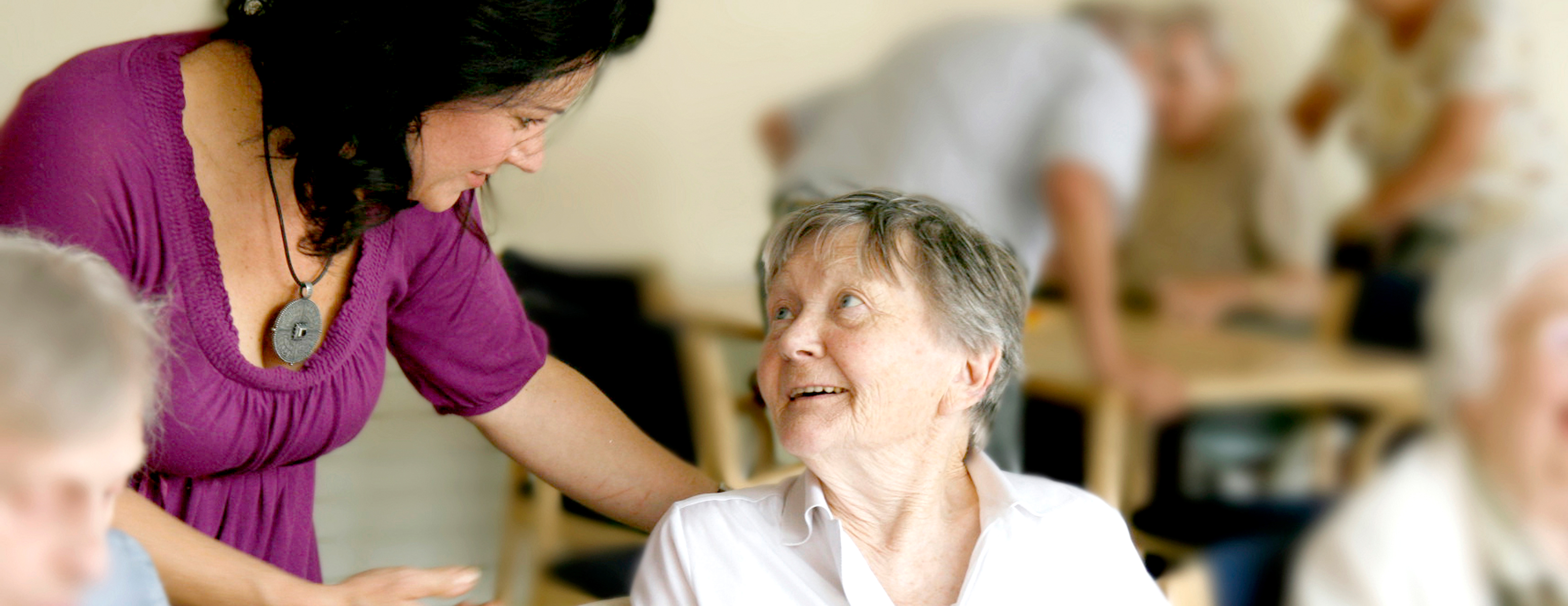 ehrenamtliche Mitarbeiterin spricht mit Seniorin